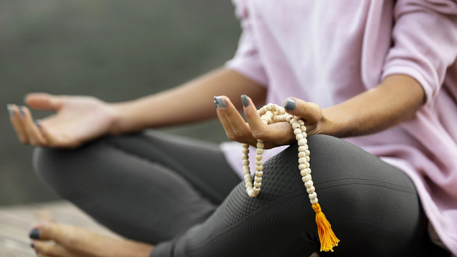 Young woman practicing yoga, holding a white bodhi seed Buddhist prayer bracelet and meditating