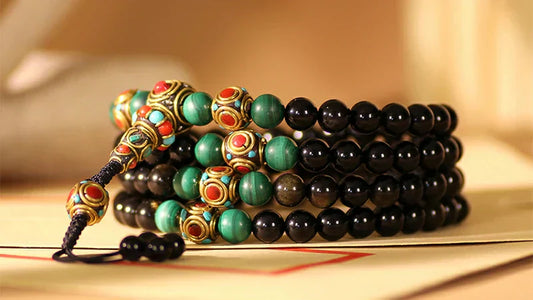 A black obsidian Mala prayer beads with golden sheen (Golden Sheen Obsidian beads), featuring an iridescent luster on each bead's surface, accented with dark-colored cord knots and tassel embellishments
