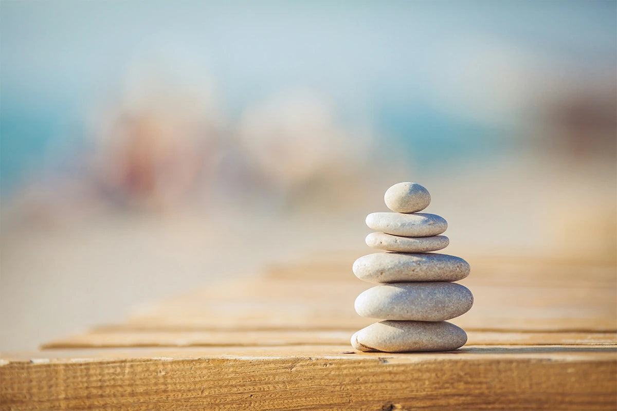 Balanced stone tower stacked with pebbles on wooden planks