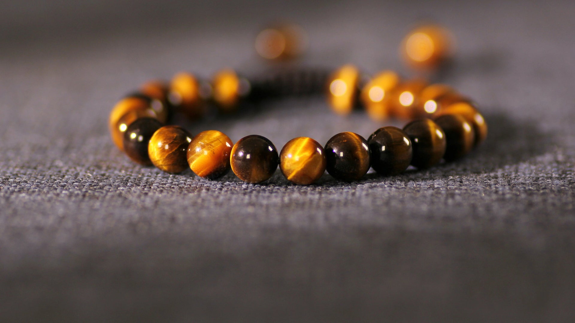 A natural tiger's eye stone bracelet, featuring beads with a golden-yellow to deep brown silky luster and a distinct cat's eye effect. Strung on an elastic cord, it is perfect for everyday wear.