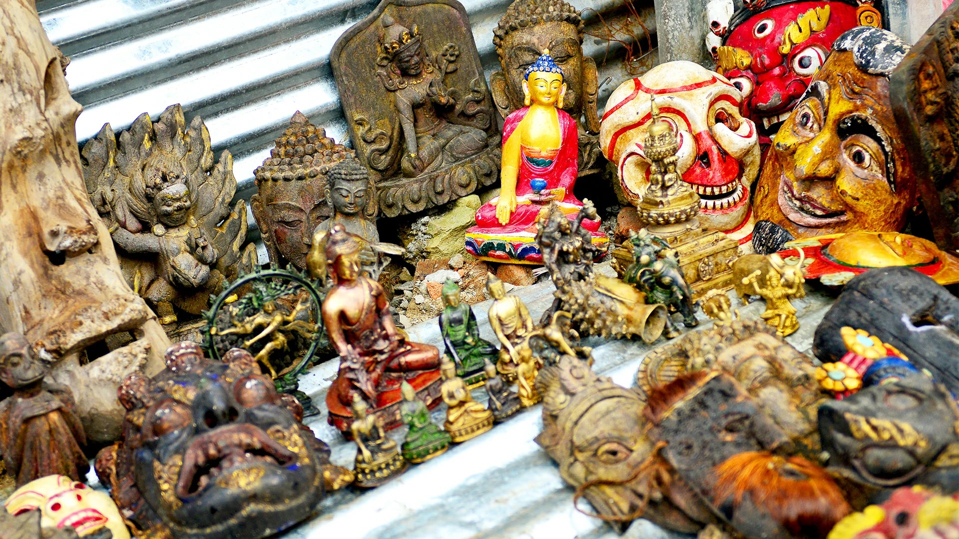 A variety of Nepalese handmade Buddha statues and masks are displayed on the market stalls