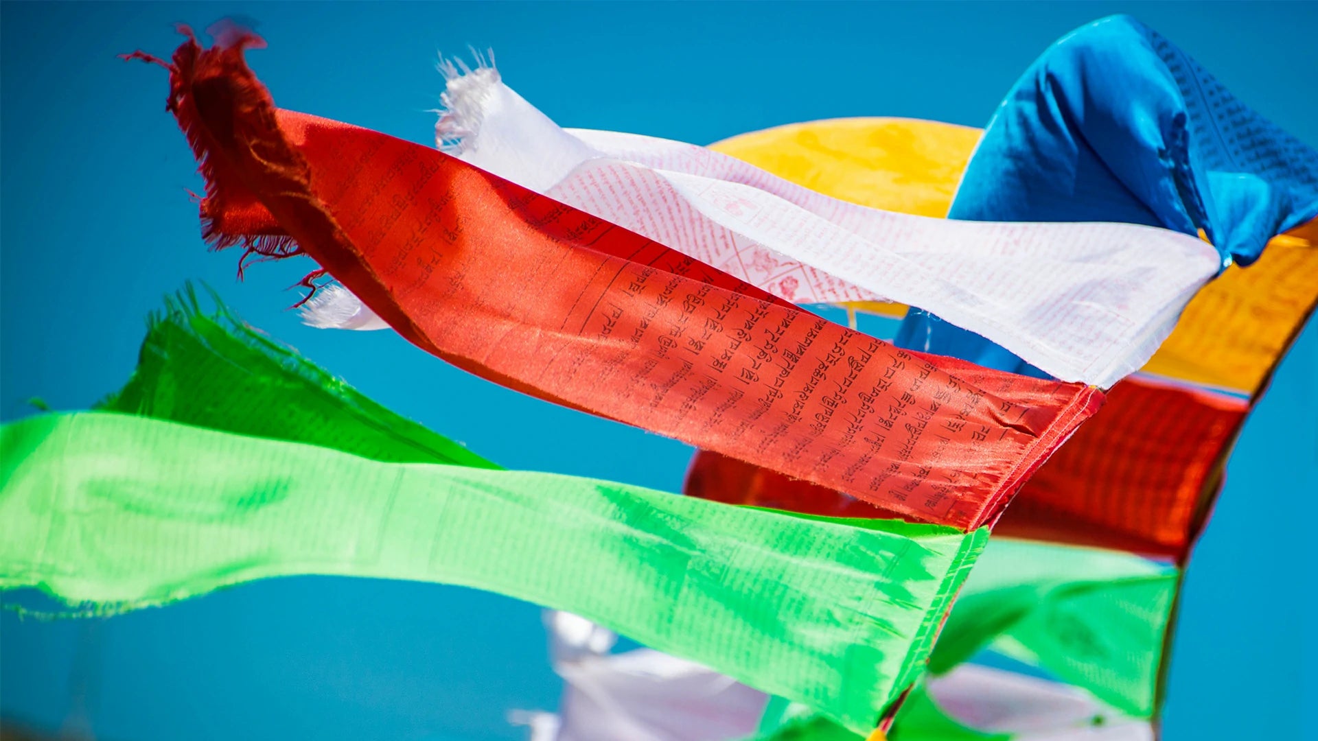 Close up of traditional Nepalese Buddhist prayer flags fluttering under blue sky and white clouds